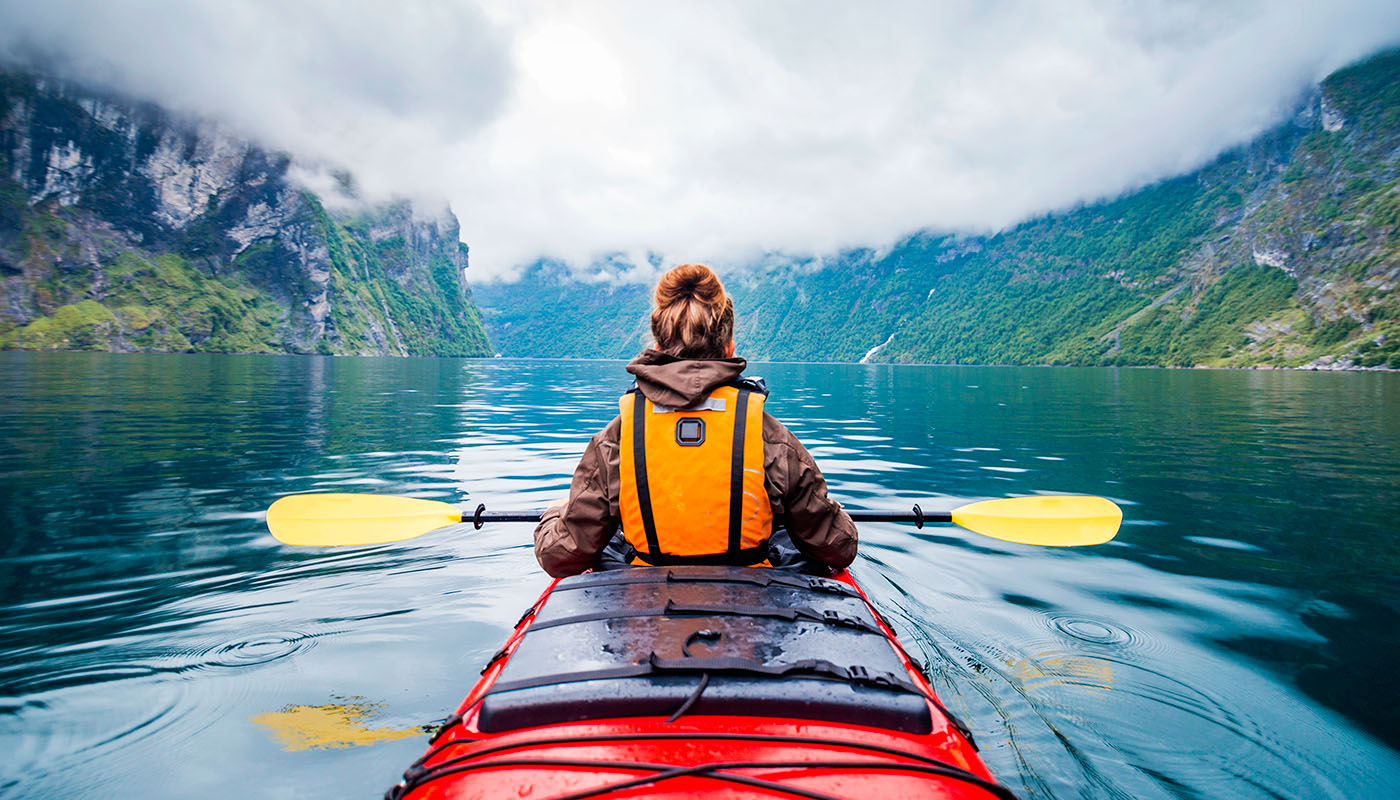 A woman kayaks through a mountain lake