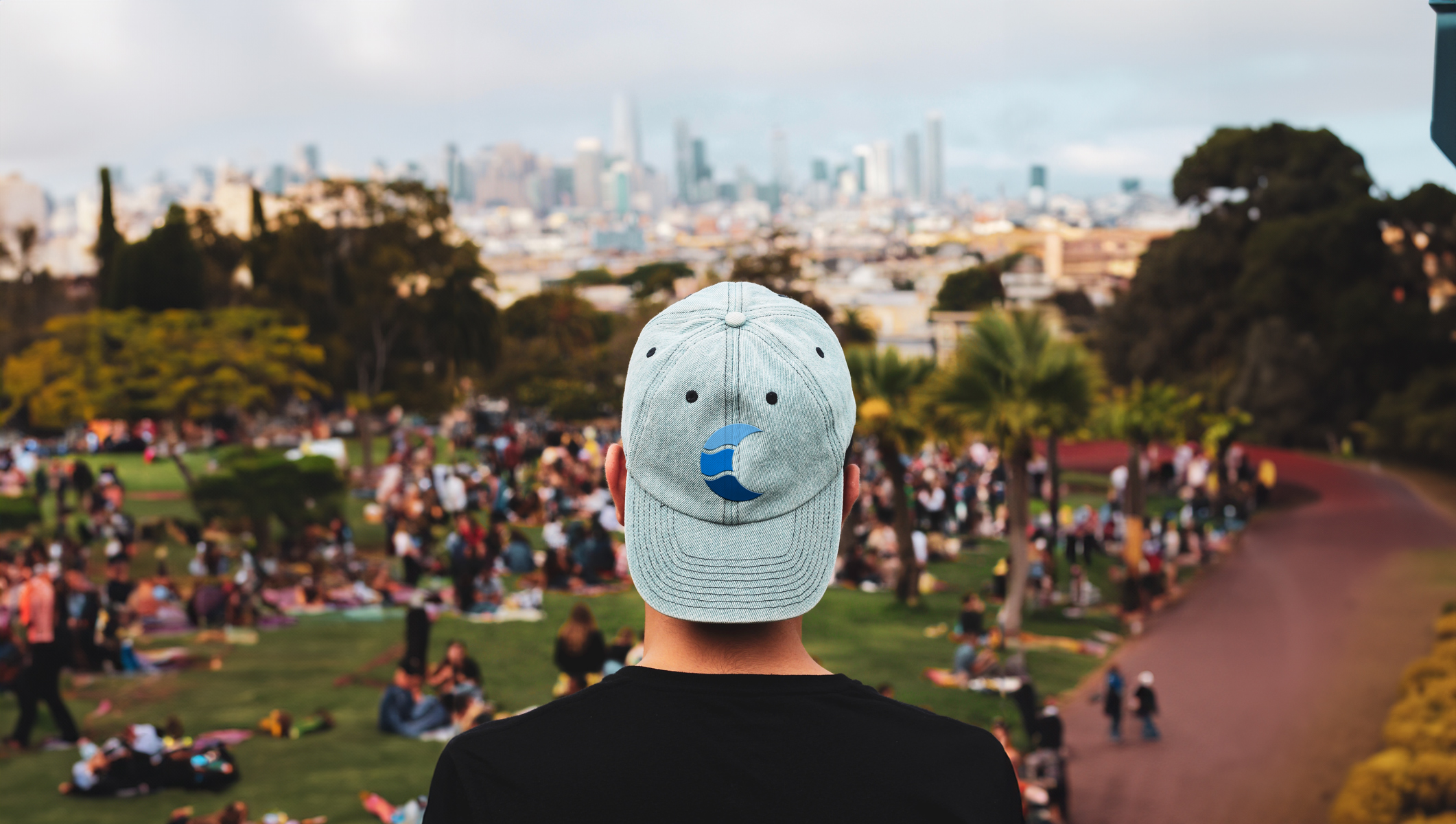 A man wearing a new hat with the City of Columbia logo looks out over a busy park
