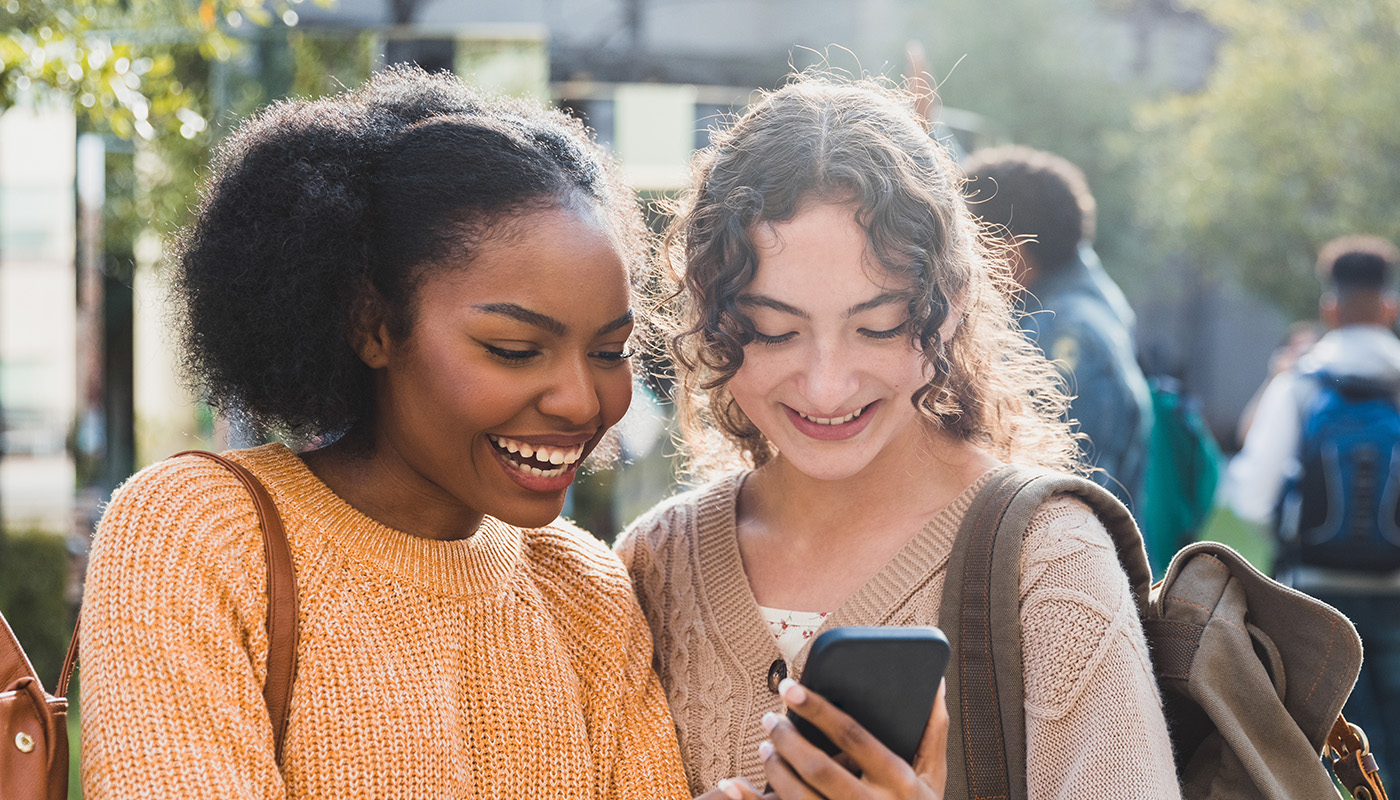Cheerful teenagers look at social media before school