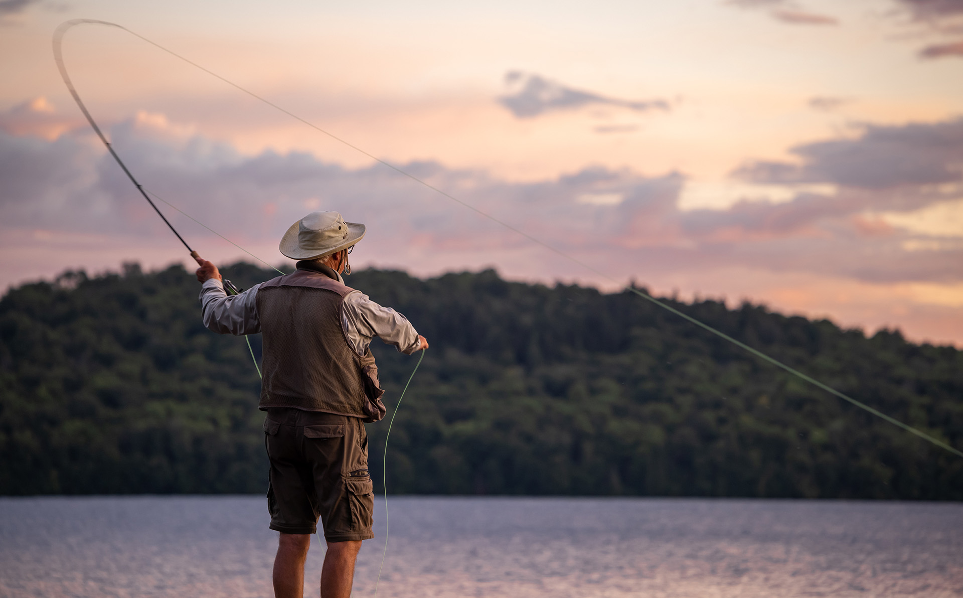 An older man fly fishes in the mountains